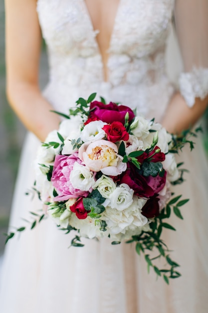 Wedding bouquet. Beautiful flowers in bride's hands in a white dress.