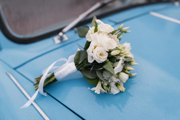 Wedding bouquet of the bride on the back of a blue retro car