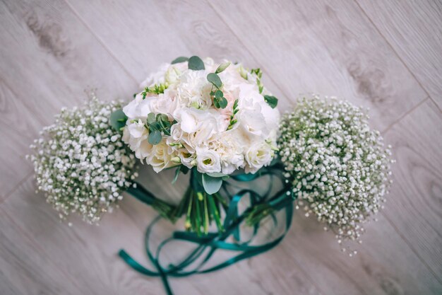 Wedding bouquet of the Bride A beautiful combination of flowers and greenery decorated with a silk ribbon lies on a wooden table