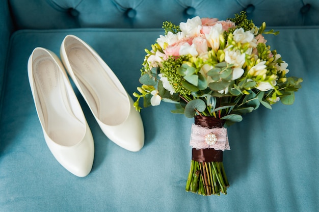 Wedding bouquet and bridesmaid shoes on blue mat