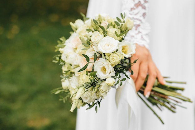 Wedding bouquet closeup photo The bride in a white dress holds beautiful flowers in her hands