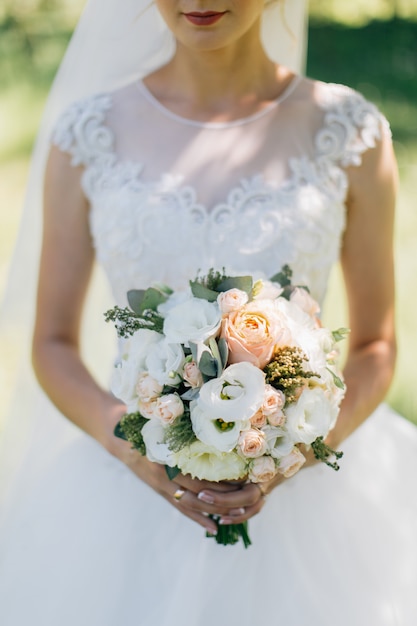 Wedding bouquet of flowers held by bride closeup. Green background