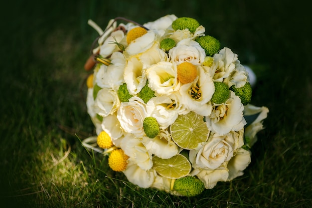 Wedding bouquet from beige roses, cinnamon, a lemon, a lime on a green grass