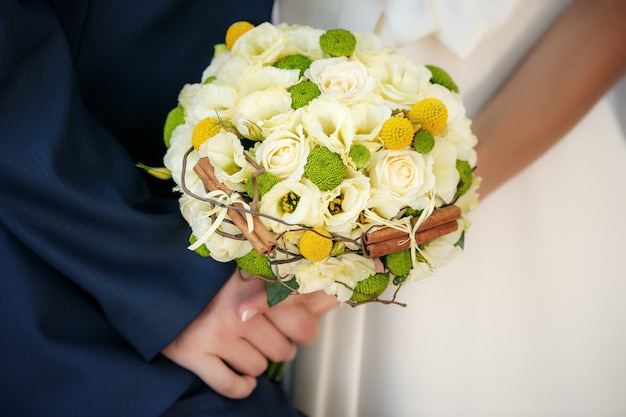 Wedding bouquet in hands of the bride and groom