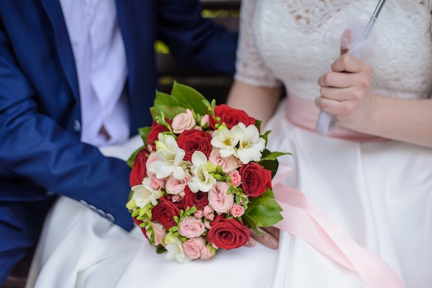 Wedding bouquet in hands of bride and groom