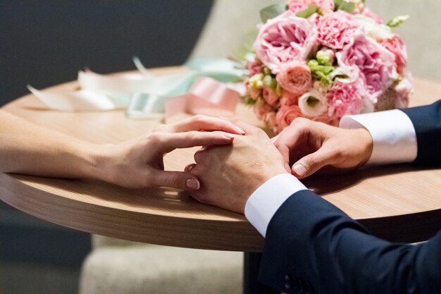 Wedding bouquet and hands of the bride and groom