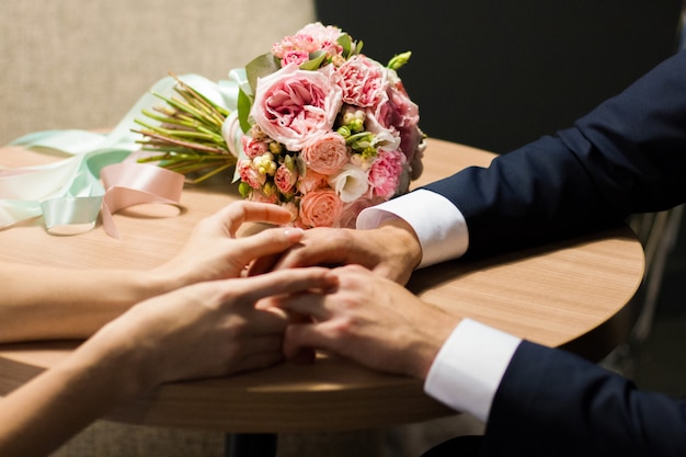 Wedding bouquet and hands of the bride and groom