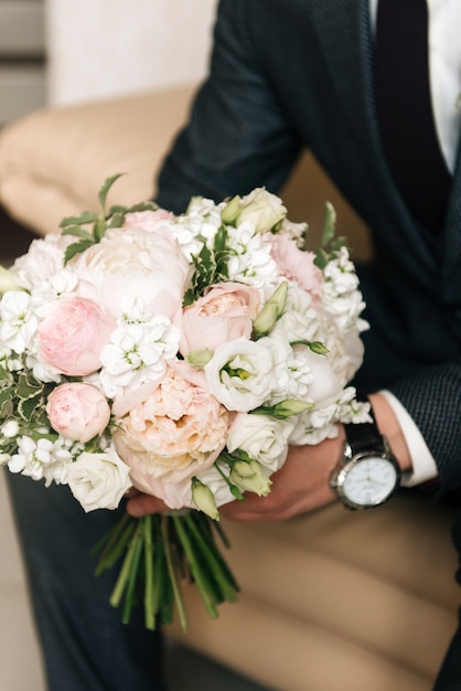 Wedding bouquet in the hands of the groom