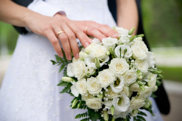 Bouquet da sposa e mani con anelli