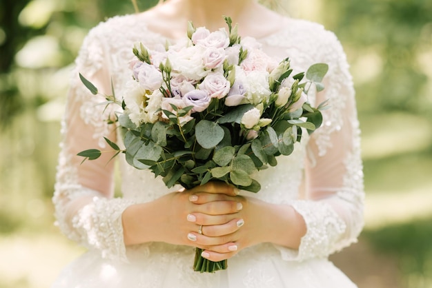 Wedding bouquet in pastel colors in the hands of the bride of roses eustoma peonies carnations and eucalyptus