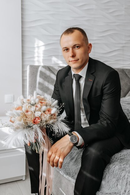 Wedding bouquet of pink roses feathers and dried flowers in the hands of the groom