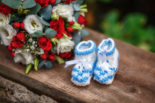 Wedding bouquet of roses and baby booties on wooden surface