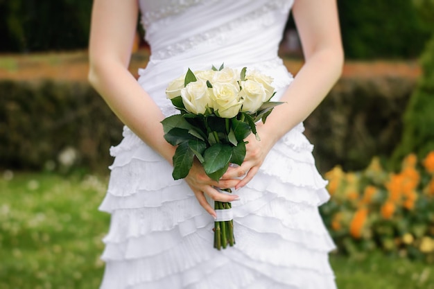 Photo wedding bouquet of roses for the bride in the hands of the bride close-up