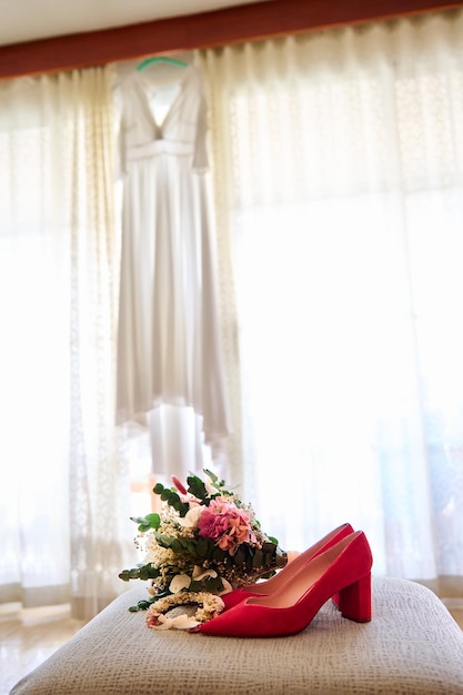 Wedding bouquet on the table with red highheeled shoes