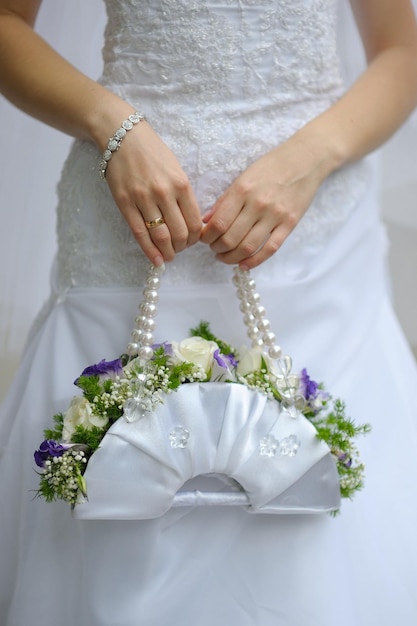 Wedding bouquet in white clutch of white flowers in hands of bride