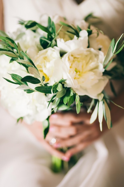 Wedding bouquet white peonies in brides hands close up in fine art style