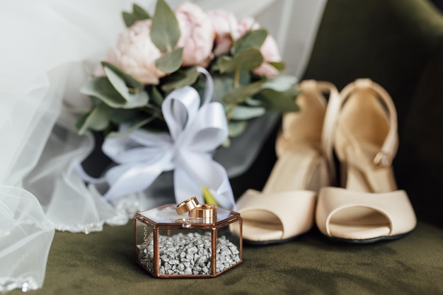 Wedding bouquet of white peonies shoes and wedding rings on a wooden background