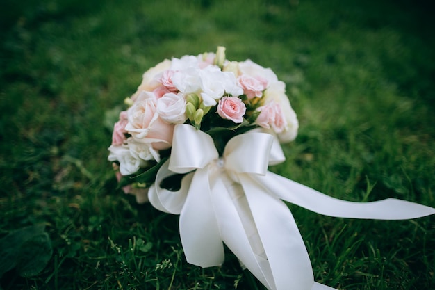 Wedding bouquet of white and pink roses lies on the green grass Wedding accessories