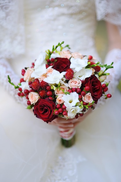 Wedding bouquet of white and red roses flowers in bride hands