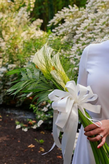 Wedding bouquet with kala flowers bride's hand outdoors