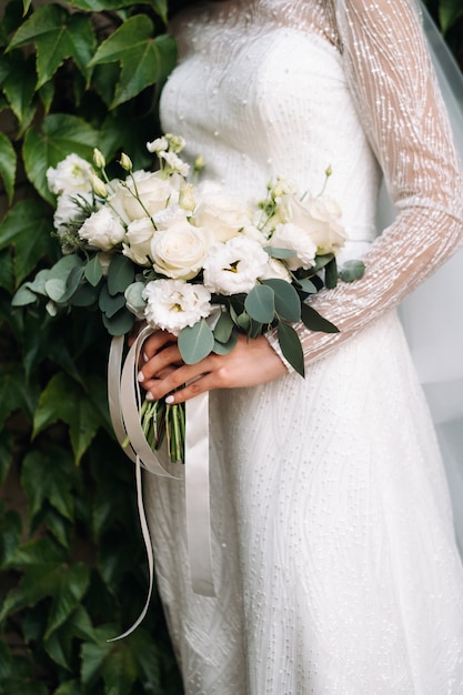 Wedding bouquet with peonies in the hands of the bride under the veil