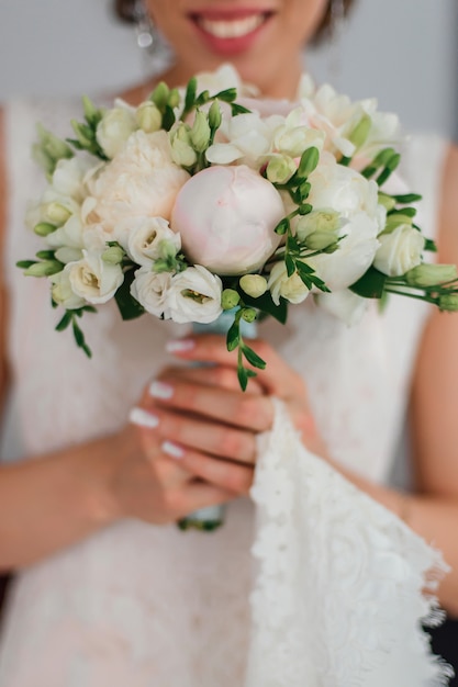 wedding bouquet with peonies in the hands of the bride