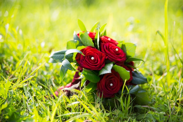 Wedding bouquet with red roses laying on grass