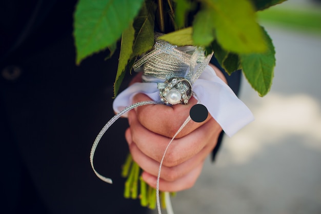 Wedding bouquet with white flowers in the hands of the groom.