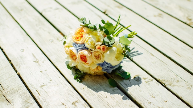 A wedding bouquet of yellow and white roses on white wooden board