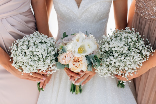 Wedding bouquets in the hands of the bride and bridesmaids. Gipsophila and peony roses