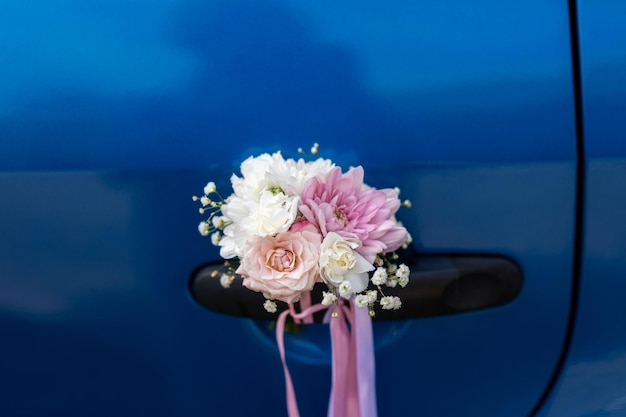 Wedding boutonniere on the handle of a blue car