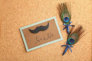Wedding boutonnieres with peacock feather and card on cork background
