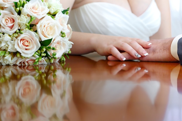 Foto il bouquet da sposa è accanto alle mani appena sposate.