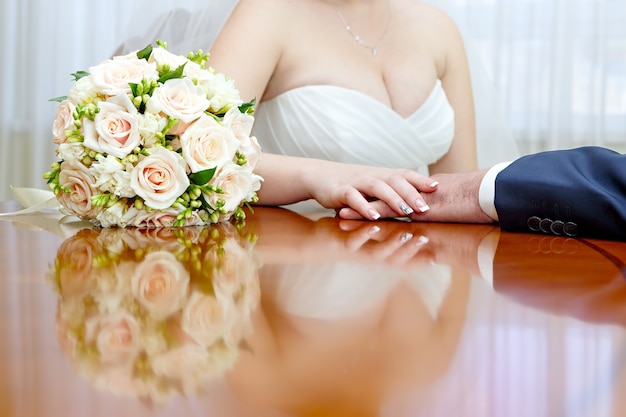 Wedding bridal bouquet is beside the hands newlywed.