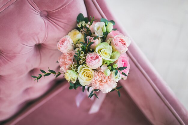 Wedding bridal bouquet lies on pink sofa