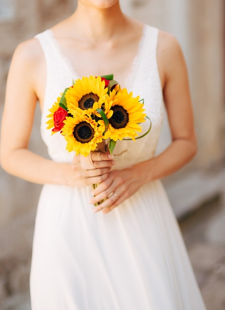 Photo wedding bridal bouquet of sunflowers in the hands of the bride