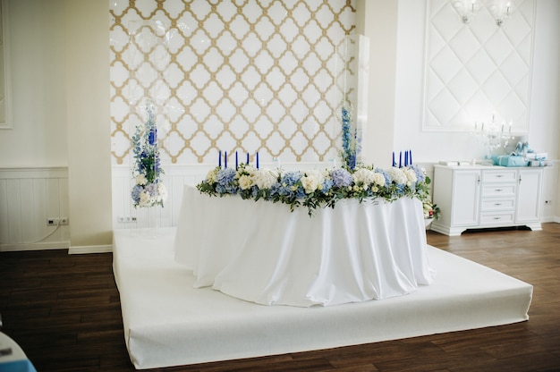Свадебный президиум стола жениха и невесты украшен множеством цветов