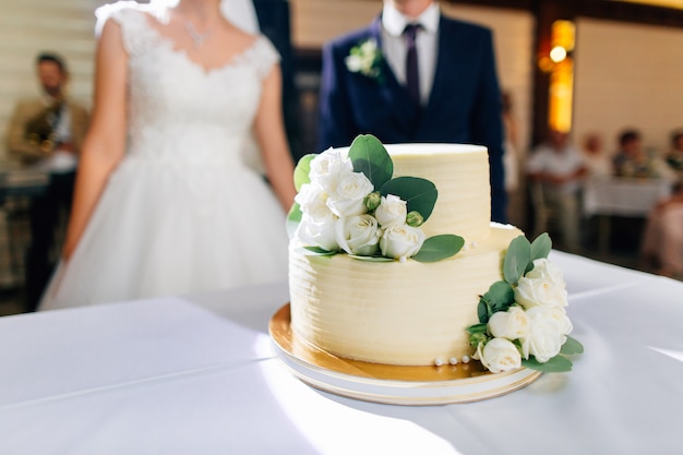 Foto torta nuziale decorata con fiori, sposi sullo sfondo