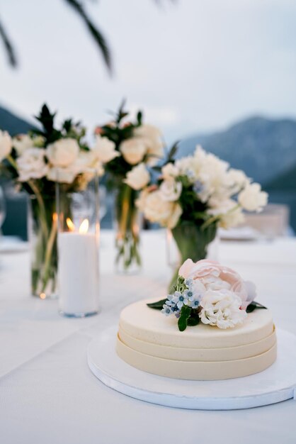 花で飾られたウェディングケーキがテーブルの上の皿に立っています