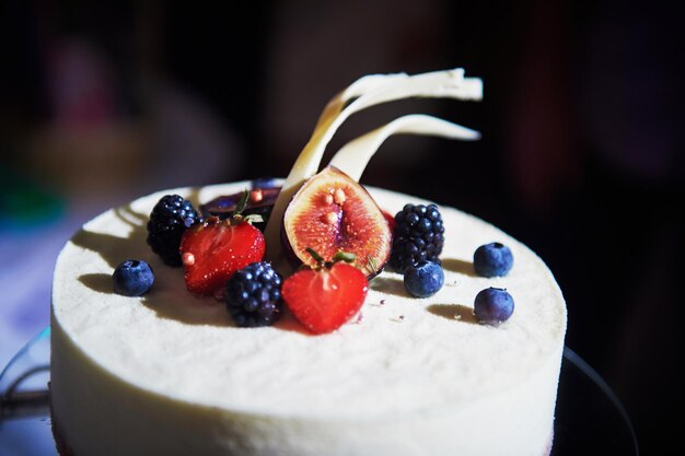 Wedding cake filled with white icing strawberries figs and blackberries