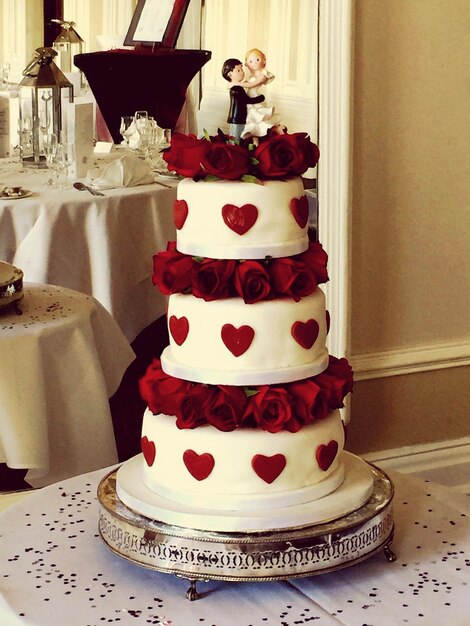 Photo wedding cake with red roses on table