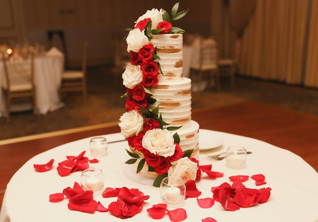 A wedding cake with red roses on top