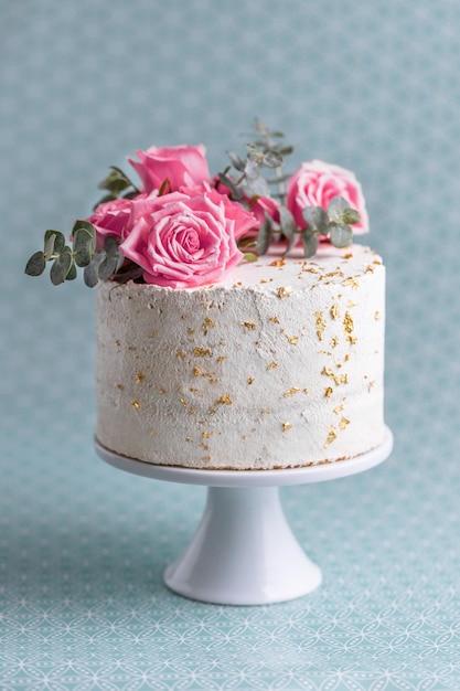 Wedding cake with roses and deco on plate. Closeup