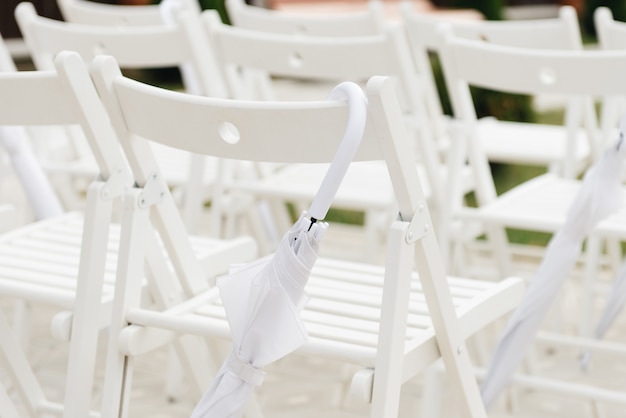 Wedding ceremony decor concept, wedding reception chairs and white umbrellas in case of rain