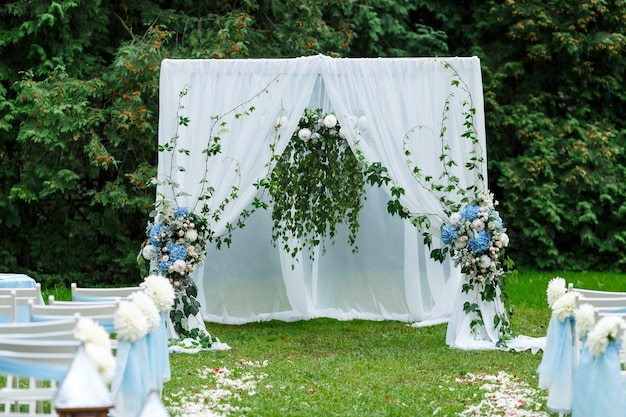 Wedding ceremony decorations arch chairs pointer and a lot of flowers in white and blue style