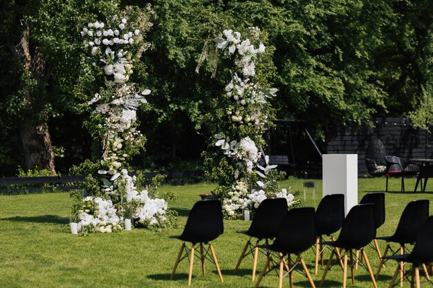 Wedding ceremony on green lawn in the garden with arch and chairs