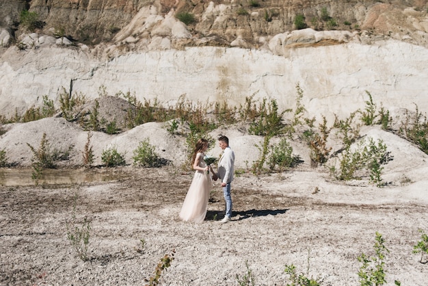 Wedding ceremony in the mountains. The bride and groom standing in front of the sandy mountains. The happy couple, a beautiful wedding in a picturesque location