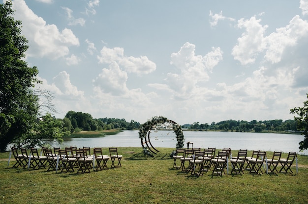 写真 緑の芝生の路上での結婚式。式典のための新鮮な花のアーチで飾る。