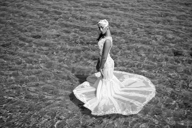 結婚式の海岸の花嫁の白いウェディングドレスは海の水に立つ濡れたウェディングドレス暑い晴れた日花嫁は幸せな夏の休暇をお楽しみください海の背景海のリゾートでのハネムーン海外での結婚式