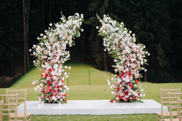 緑の芝生の路上での結婚式。式典のための新鮮な花のアーチで飾る。